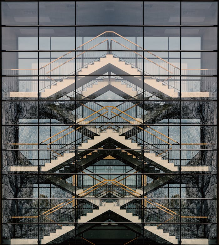Geometric reflection of a modern staircase on a glass building facade.